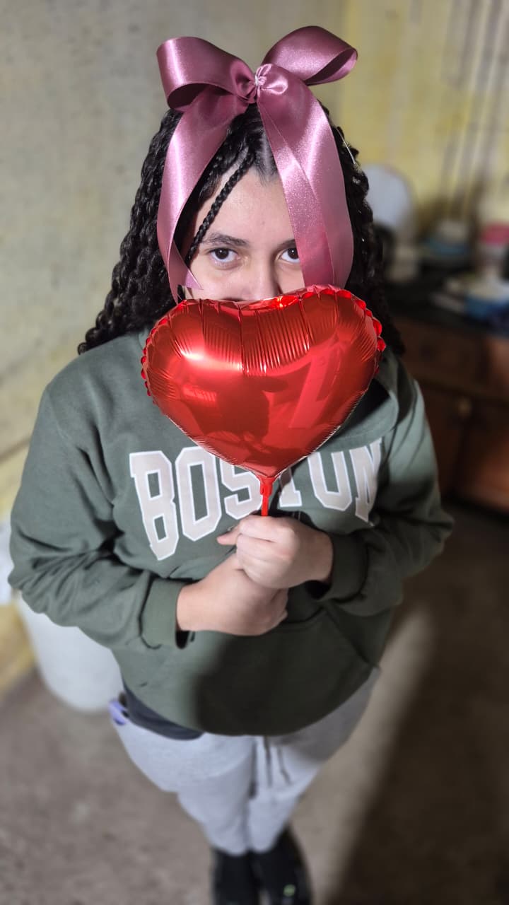 Ela com um laço rosa e um balão vermelho de coração